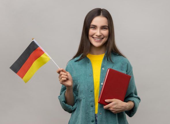 optimistic-woman-holding-hands-book-german-flag-education-courses-abroad